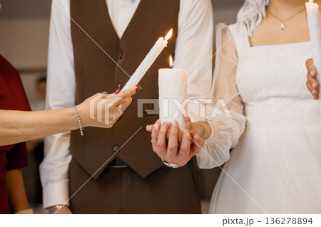 Wedding Couple Lighting Unity Candle Together in Elegant Ceremony with Soft Warm Glow and White Attire 136278894
