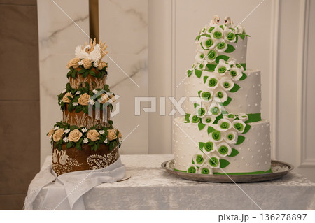 Elegant Two-Tier Wedding Cake with White and Green Floral Decorations and Swan Toppers in a Luxurious室内 Setting 136278897