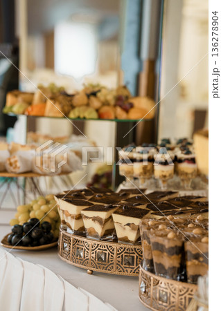 Elegant Dessert Buffet Display with Tiramisu, Fruit, and Pastries on Tiered Gold Stands in Luxurious Event Setting 136278904