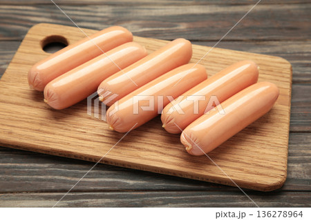 Fresh chicken sausages on cutting board on brown background. 136278964