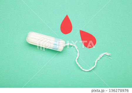 Composition with menstrual tampons and blood drop made of paper on mint background Composition with menstrual tampons and blood drop made of paper on mint background 136278976
