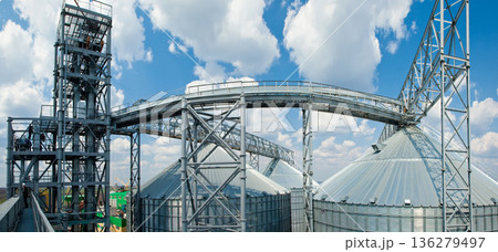 Wide panoramic view of a modern industrial grain terminal with silver silos under a blue sky Wide panoramic view of a modern industrial grain terminal with silver silos under a blue sky 136279497