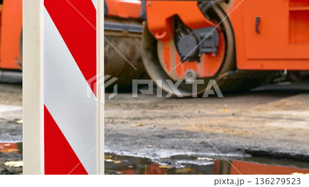 A road safety sign post at a road construction site with an asphalt roller A road safety sign post at a road construction site with an asphalt roller 136279523