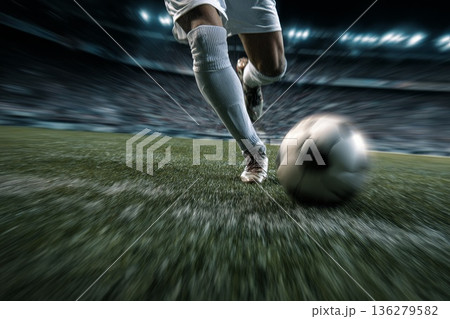 A football player kicks a ball hard close-up on the stadium pitch 136279582