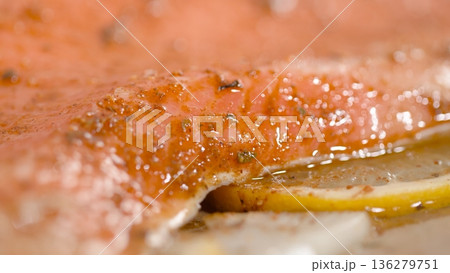 Fresh salmon fillet being prepared with spices and lemon slices on a cutting board before cooking Fresh salmon fillet being prepared with spices and lemon slices on a cutting board before cooking 136279751