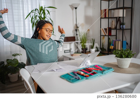Young girl stretching arms during online education at home 136280680