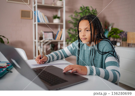 Young girl learning online from home with laptop and pencil 136280699