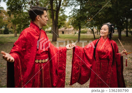Couple celebrating Chinese wedding ceremony holding hands outdoors Couple celebrating Chinese wedding ceremony holding hands outdoors 136280790