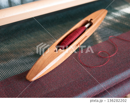 Wooden shuttle and vibrant threads highlights the beauty of craftsmanship. Artistry in weaving 136282202
