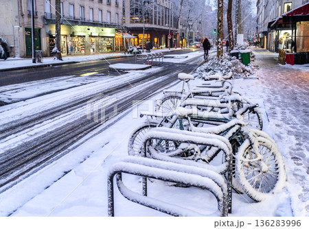 Paris, France. Winter street scene features snow covered bicycles parked on the sidewalk along Avenue de Clichy during a cold day Paris, France. Winter street scene features snow covered bicycles parked on the sidewalk along Avenue de Clichy during a cold day 136283996