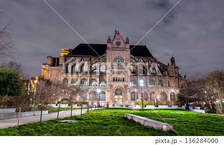 Church of Saint-Eustache in the 1st district of Paris, France. Historic Gothic and Renaissance architecture features illuminated southern facade and flying buttresses viewed from Nelson Mandela Garden 136284000