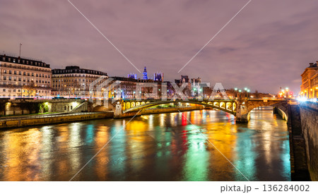 Pont Notre-Dame bridge crosses the Seine river with colorful city light reflections on the water during the evening in Paris, France Pont Notre-Dame bridge crosses the Seine river with colorful city light reflections on the water during the evening in Paris, France 136284002