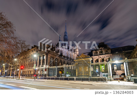 Historic Palais de Justice entrance gate and Sainte-Chapelle spire illuminated at night on Ile de la Cite in Paris, France 136284003