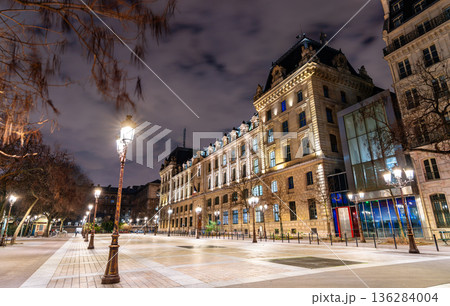 Place Louis Lepine square features historic lamp posts and the illuminated facade of the Prefecture of Police building on Ile de la Cite in Paris, France 136284004