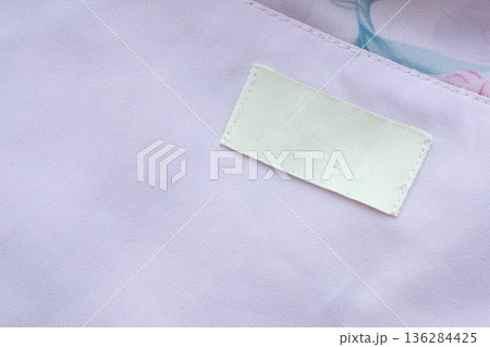 Blank white laundry care clothes label on purple shirt fabric texture background Blank white laundry care clothes label on purple shirt fabric texture background 136284425