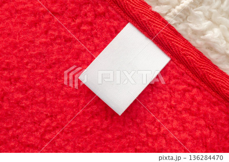 Blank white laundry care clothes label on red shirt fabric texture background 136284470