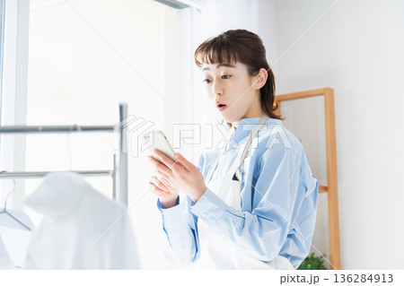 家事をしながらスマホを見る若い女性 家事をしながらスマホを見る若い女性 136284913
