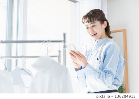 家事をしながらスマホを見る若い女性 家事をしながらスマホを見る若い女性 136284915