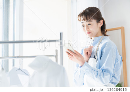 家事をしながらスマホを見る若い女性 家事をしながらスマホを見る若い女性 136284916