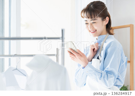 家事をしながらスマホを見る若い女性 家事をしながらスマホを見る若い女性 136284917
