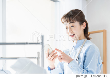 家事をしながらスマホを見る若い女性 家事をしながらスマホを見る若い女性 136284919