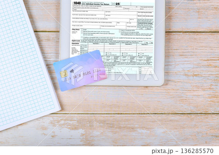 Federal 1040 tax form, credit card are placed in accounting workspace setting preparation for tax filing. 136285570