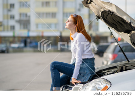 Young stressed woman driver near broken car with popped hood waiting for assistance. Young stressed woman driver near broken car with popped hood waiting for assistance. 136286789