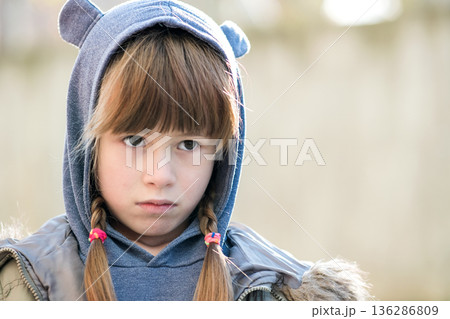 Portrait of happy child girl in warm clothes in autumn outdoors. 136286809