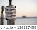 Rope Wrapped Around Wooden Post by Calm Sea at Sunset 136287459