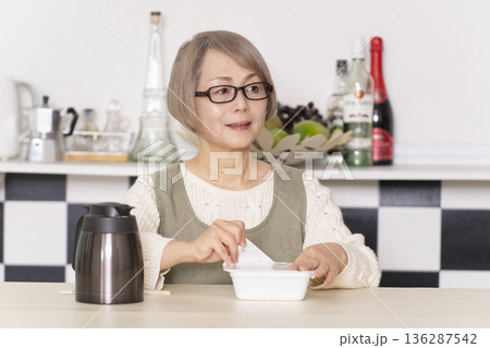 キッチンでカップ麺にお湯を入れるシニア女性 136287542