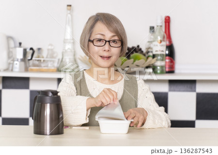 キッチンでカップ麺にお湯を入れるシニア女性 キッチンでカップ麺にお湯を入れるシニア女性 136287543