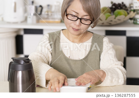 キッチンでカップ麺にお湯を入れるシニア女性 キッチンでカップ麺にお湯を入れるシニア女性 136287555