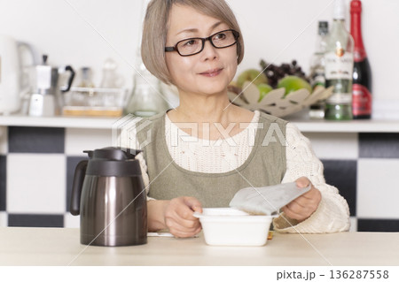 キッチンでカップ麺にお湯を入れるシニア女性 キッチンでカップ麺にお湯を入れるシニア女性 136287558