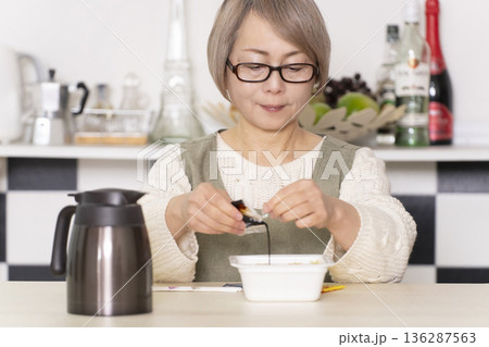 キッチンでカップ麺にお湯を入れるシニア女性 136287563