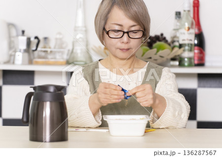 キッチンでカップ麺にお湯を入れるシニア女性 キッチンでカップ麺にお湯を入れるシニア女性 136287567