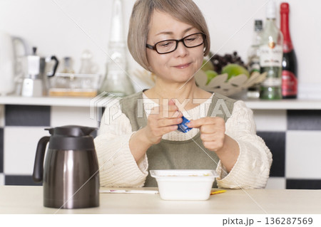 キッチンでカップ麺にお湯を入れるシニア女性 キッチンでカップ麺にお湯を入れるシニア女性 136287569