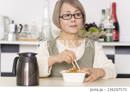キッチンでカップ麺にお湯を入れるシニア女性 キッチンでカップ麺にお湯を入れるシニア女性 136287572