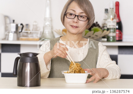 キッチンでカップ麺にお湯を入れるシニア女性 136287574