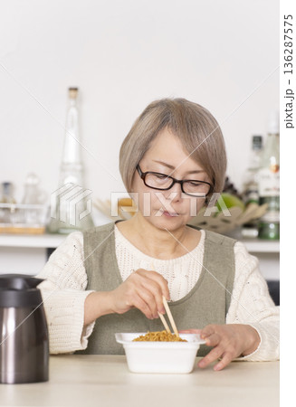 キッチンでカップ麺にお湯を入れるシニア女性 キッチンでカップ麺にお湯を入れるシニア女性 136287575