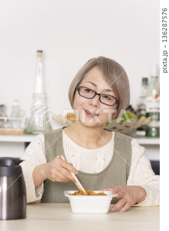 キッチンでカップ麺にお湯を入れるシニア女性 キッチンでカップ麺にお湯を入れるシニア女性 136287576