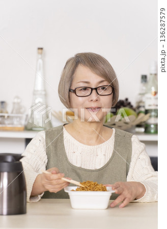 キッチンでカップ麺にお湯を入れるシニア女性 キッチンでカップ麺にお湯を入れるシニア女性 136287579