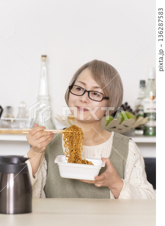 キッチンでカップ麺にお湯を入れるシニア女性 キッチンでカップ麺にお湯を入れるシニア女性 136287583