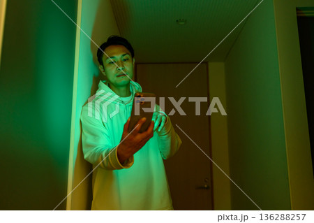 廊下でスマホを見る男性 136288257