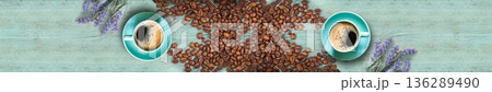 Panoramic top view of two coffee cups surrounded by lavender and plenty of roasted beans on blue wood 136289490