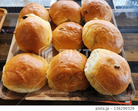 Freshly Baked Golden Brown Raisin Buns on a Rustic Wooden Serving Tray Freshly Baked Golden Brown Raisin Buns on a Rustic Wooden Serving Tray 136290326