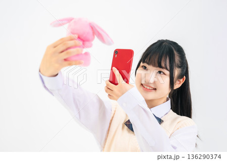 ぬいぐるみをスマホで撮影する女子学生 136290374
