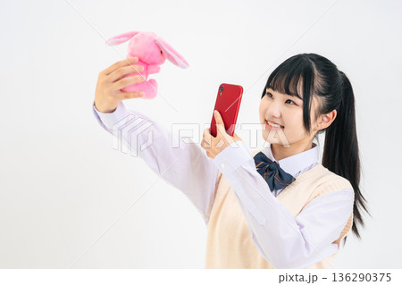 ぬいぐるみをスマホで撮影する女子学生 136290375