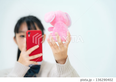 ぬいぐるみをスマホで撮影する女子学生 136290402