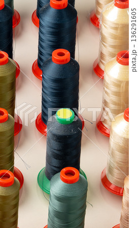 Rows of thread spools in various colors on a flat surface in a crafting area Rows of thread spools in various colors on a flat surface in a crafting area 136291605