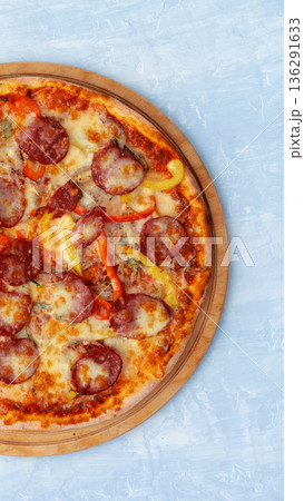 Pizza topped with pepperoni and bell peppers on a wooden board ready for serving Pizza topped with pepperoni and bell peppers on a wooden board ready for serving 136291633